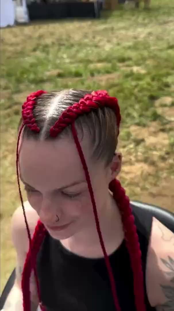 Long red and black braids with red extensions falling past the waist, worn outdoors