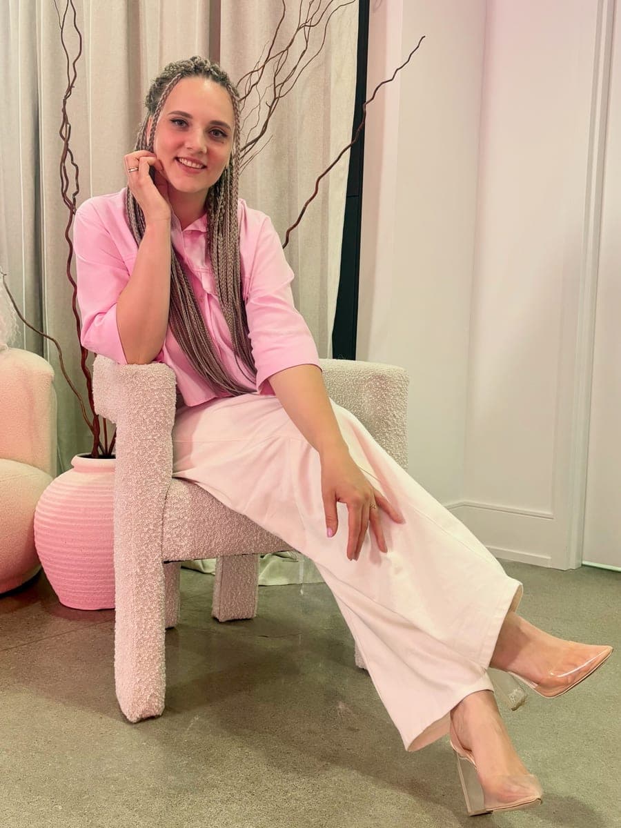 Anna seated in the studio, wearing her own hair in long ash-blonde braids